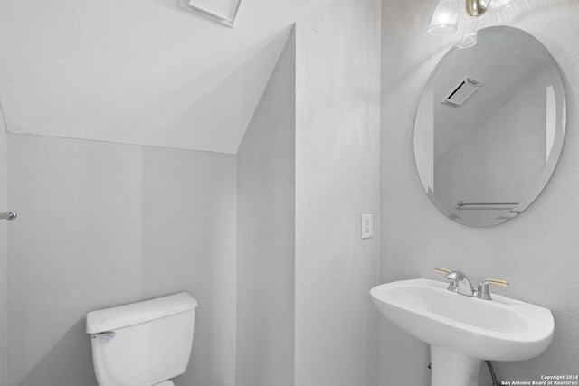 bathroom with lofted ceiling, sink, and toilet