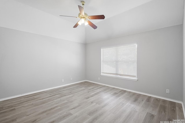 empty room with ceiling fan, vaulted ceiling, and light hardwood / wood-style flooring