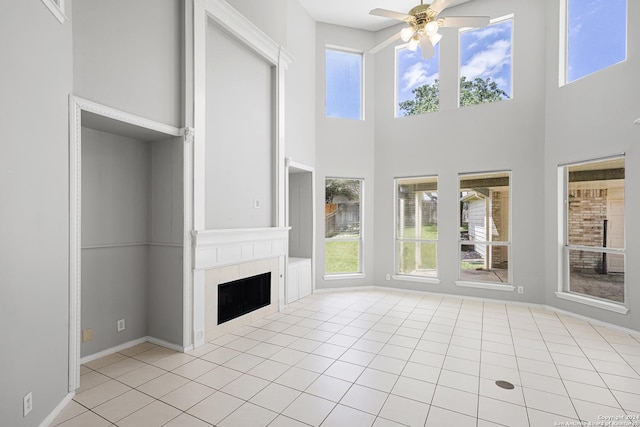 unfurnished sunroom featuring ceiling fan, a tile fireplace, and a wealth of natural light