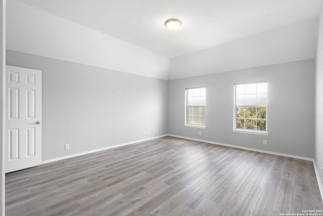 empty room featuring vaulted ceiling and light hardwood / wood-style flooring