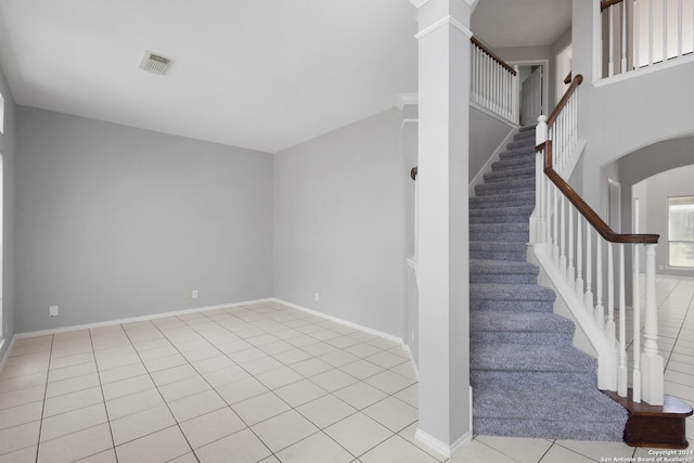 stairway featuring ornate columns and tile patterned floors