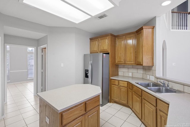 kitchen with stainless steel refrigerator with ice dispenser, sink, light tile patterned floors, and decorative backsplash