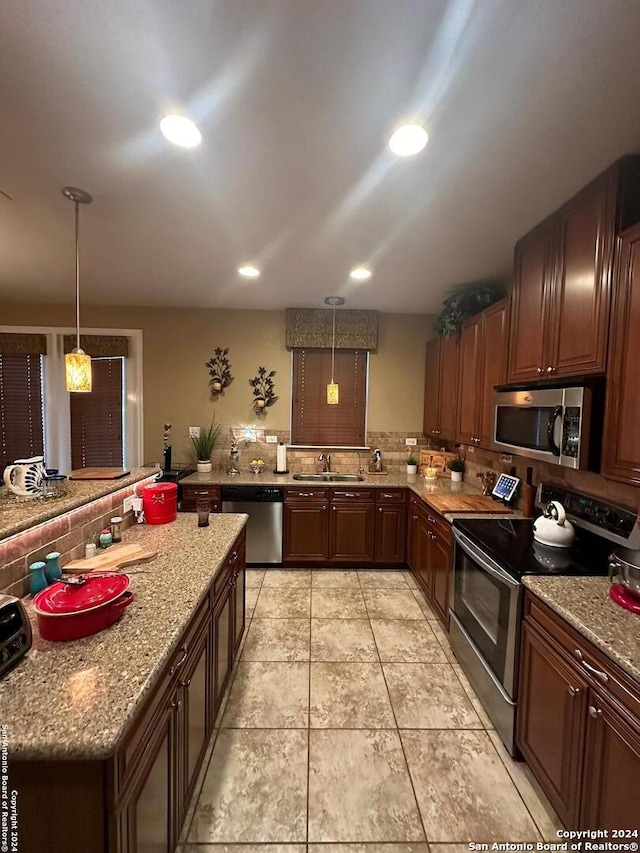 kitchen with tasteful backsplash, recessed lighting, hanging light fixtures, a sink, and appliances with stainless steel finishes