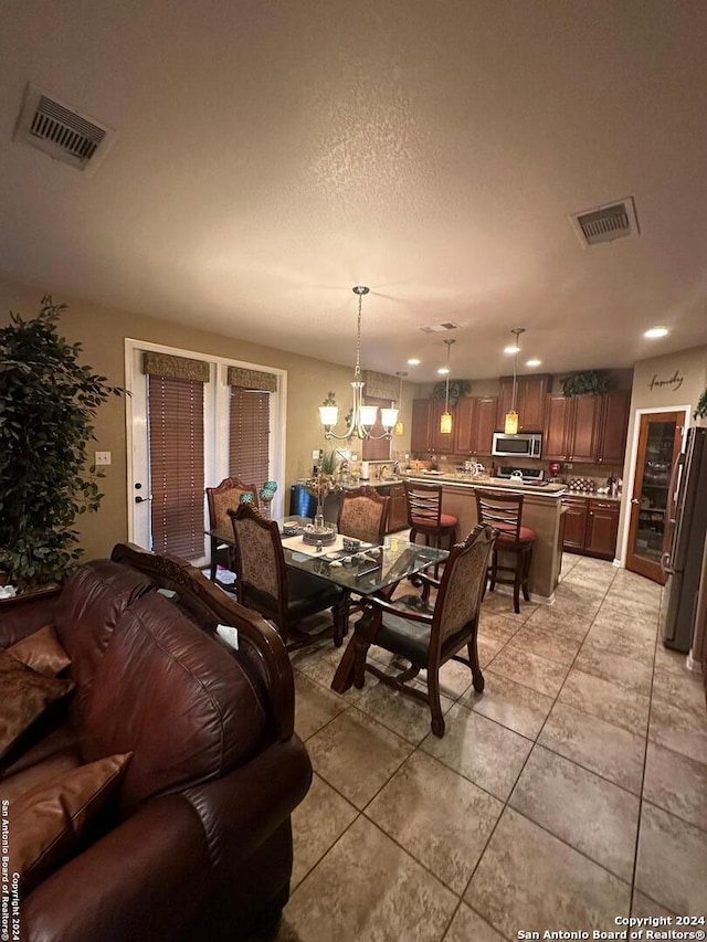 living room with a textured ceiling, visible vents, a chandelier, and light tile patterned floors