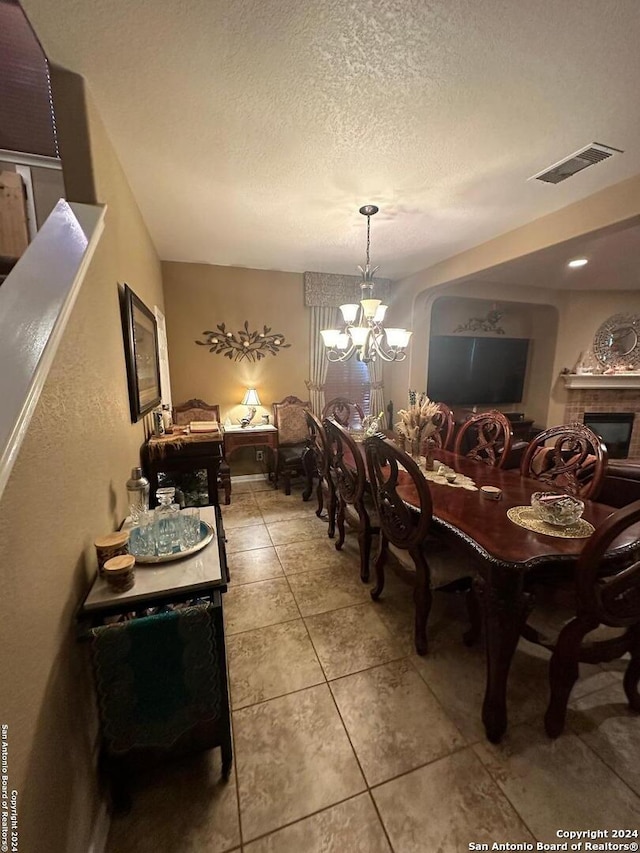 tiled dining room featuring a textured ceiling, visible vents, and a chandelier
