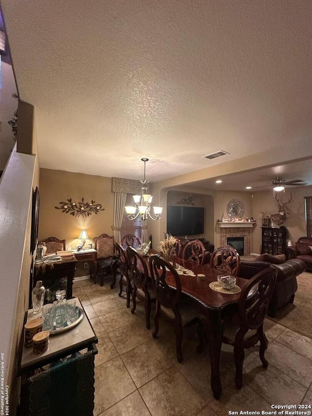 dining room with a textured ceiling, visible vents, a chandelier, a fireplace, and light tile patterned floors