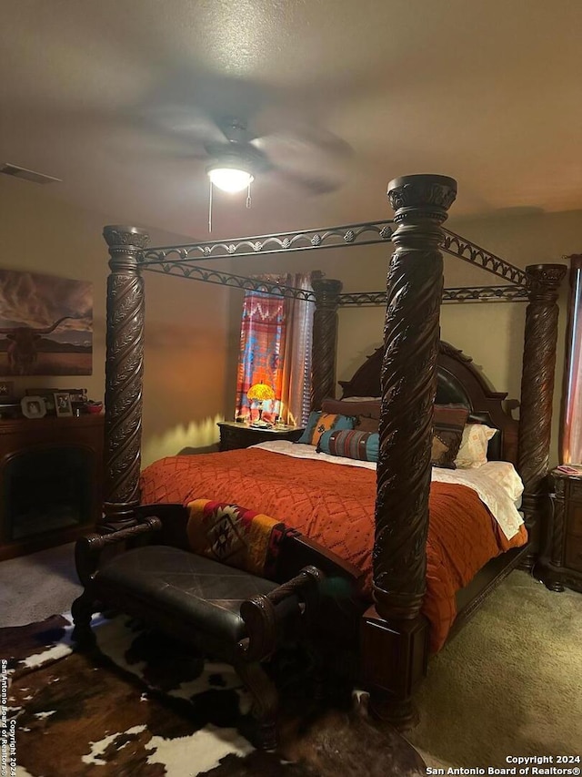 carpeted bedroom with a fireplace, visible vents, and ceiling fan