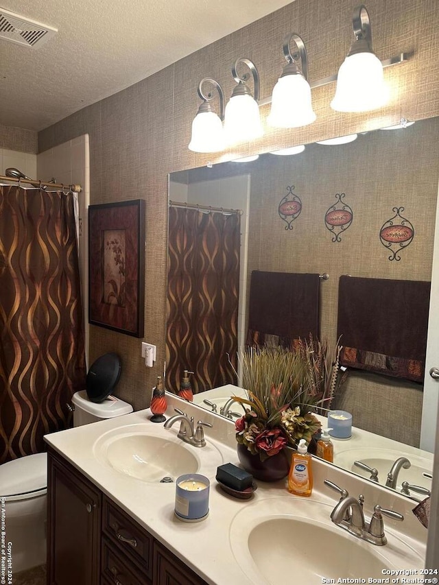 bathroom with vanity, toilet, and a textured ceiling