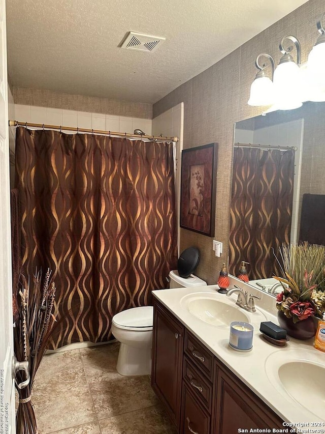 bathroom with double vanity, a sink, a textured ceiling, and visible vents