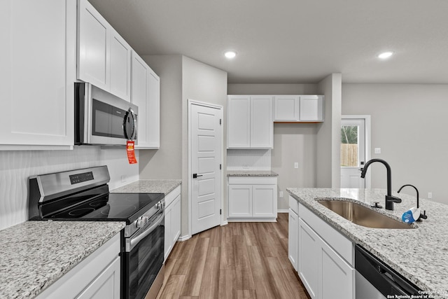 kitchen featuring stainless steel appliances, light stone countertops, sink, and white cabinets