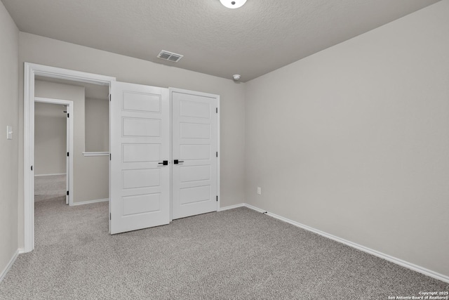 unfurnished bedroom with carpet flooring, a textured ceiling, and a closet