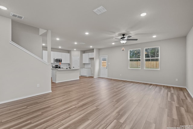 unfurnished living room with ceiling fan, sink, and light hardwood / wood-style floors