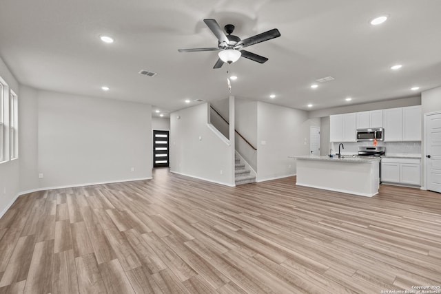 unfurnished living room featuring ceiling fan, sink, and light hardwood / wood-style floors