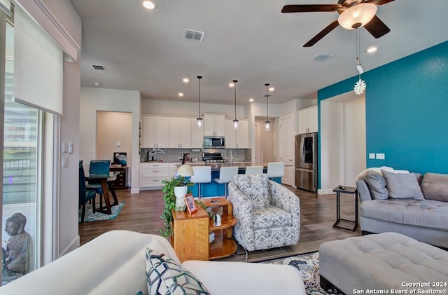 living room with dark hardwood / wood-style floors, sink, and ceiling fan