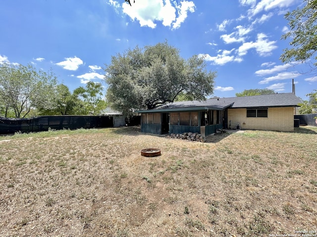 back of house featuring a fire pit, a sunroom, and a yard