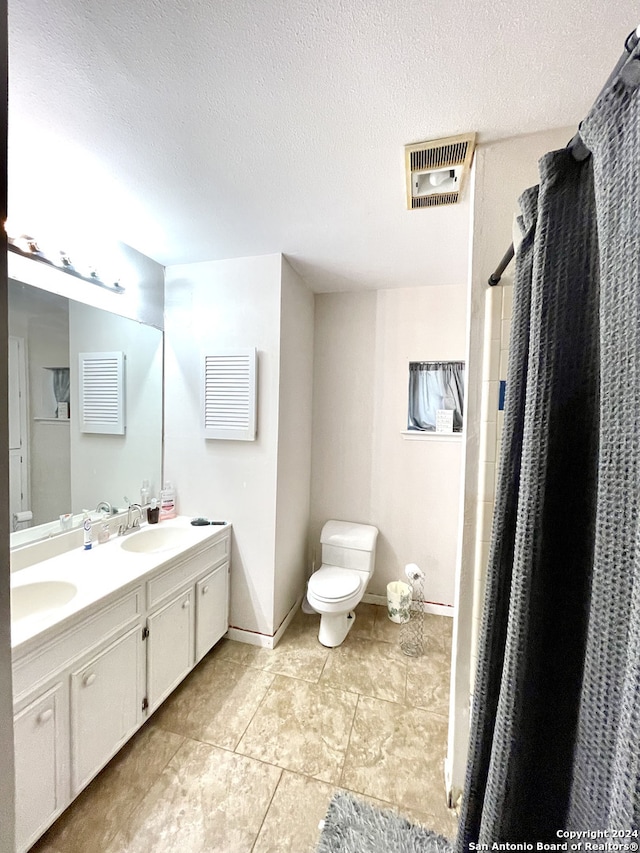 bathroom with vanity, toilet, a textured ceiling, and tile patterned floors