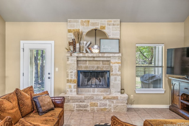 tiled living room with a stone fireplace