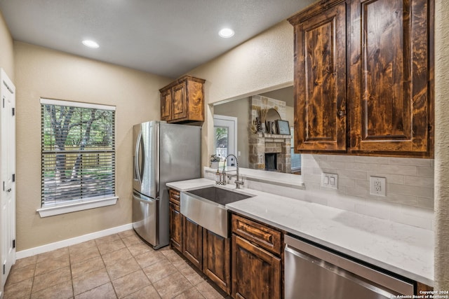 kitchen featuring light tile patterned flooring, appliances with stainless steel finishes, tasteful backsplash, sink, and light stone countertops