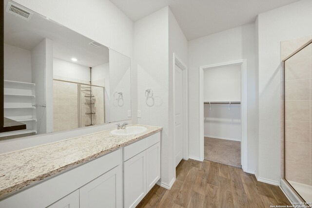 bathroom with a shower with door, vanity, and hardwood / wood-style floors