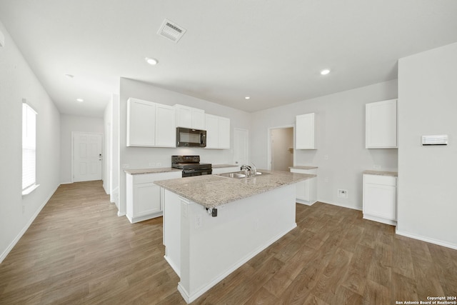 kitchen featuring a kitchen island with sink, white cabinetry, wood-type flooring, sink, and range with electric cooktop