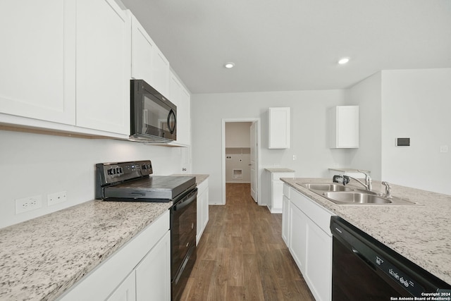 kitchen with dark hardwood / wood-style flooring, light stone counters, white cabinetry, black appliances, and sink