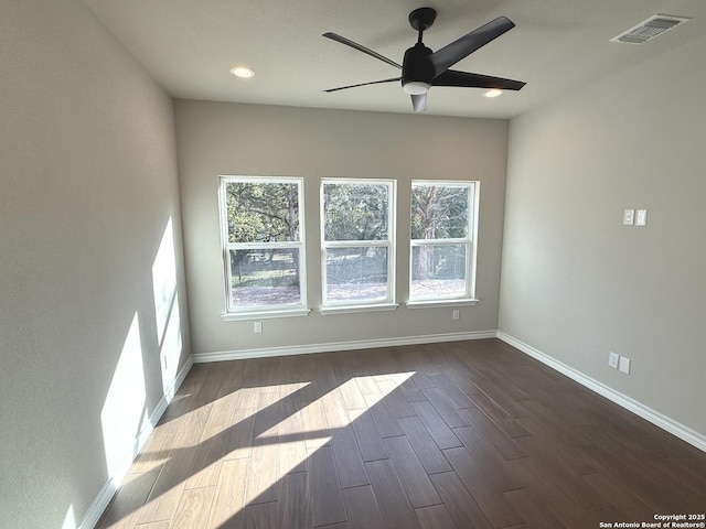 unfurnished room featuring dark wood-style floors, a healthy amount of sunlight, visible vents, and baseboards