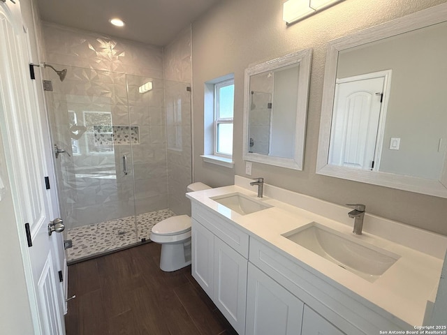 full bathroom featuring a stall shower, a sink, toilet, and wood finished floors