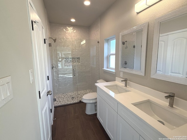 full bathroom featuring a stall shower, a sink, toilet, and wood finished floors