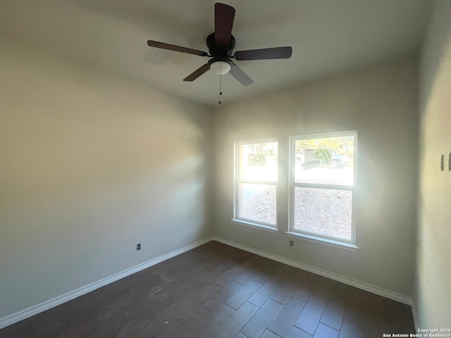 empty room featuring ceiling fan, baseboards, and dark wood-type flooring