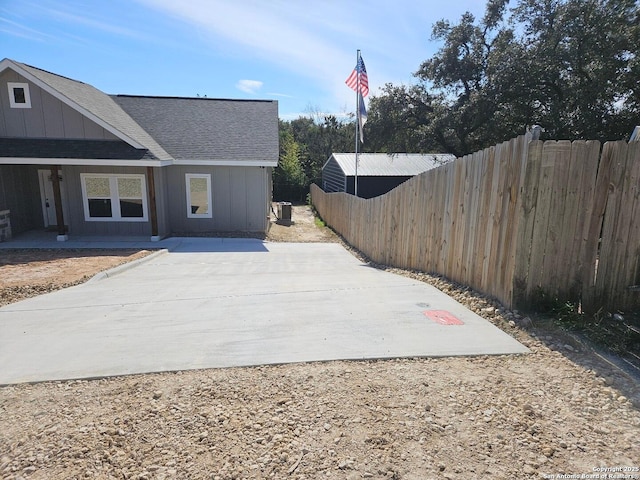 view of home's exterior featuring cooling unit, a shingled roof, fence, and board and batten siding