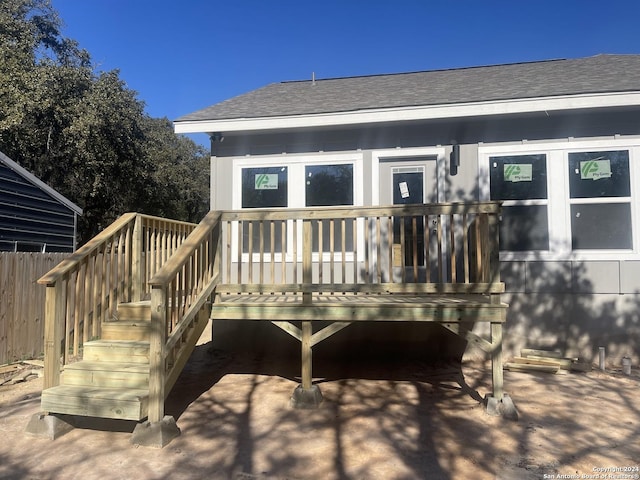 exterior space with a wooden deck, stairway, and roof with shingles