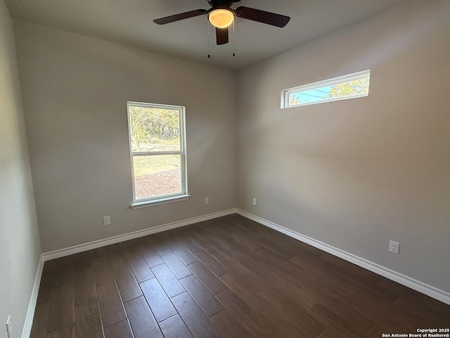 empty room with dark wood-style floors, a ceiling fan, a wealth of natural light, and baseboards