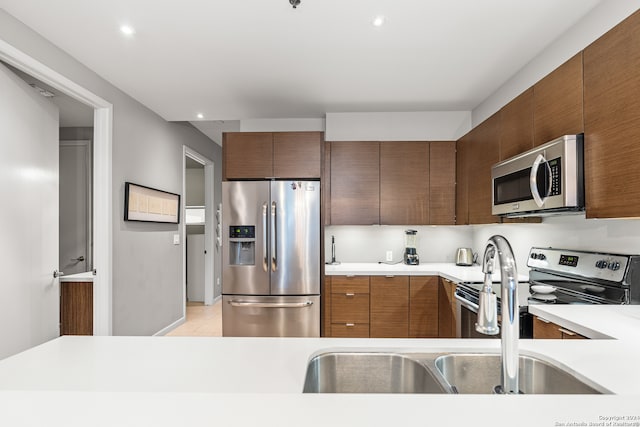 kitchen with appliances with stainless steel finishes, light tile patterned flooring, and sink