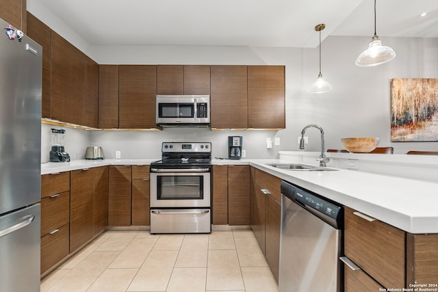 kitchen featuring light tile patterned flooring, stainless steel appliances, hanging light fixtures, sink, and kitchen peninsula