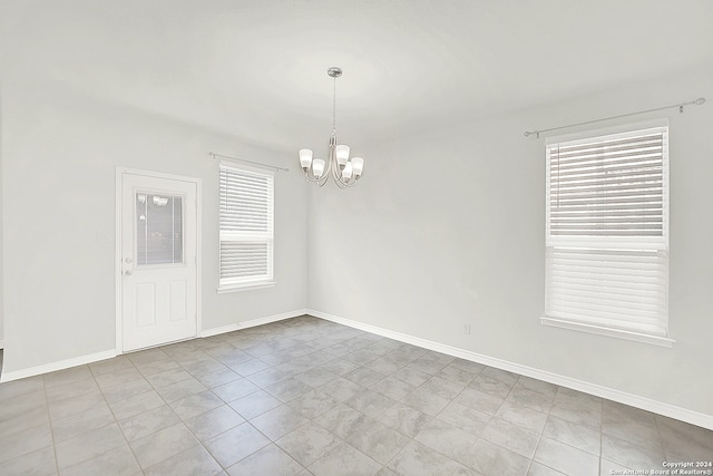 tiled spare room with an inviting chandelier