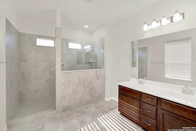 bathroom with tile patterned floors, double vanity, and tiled shower