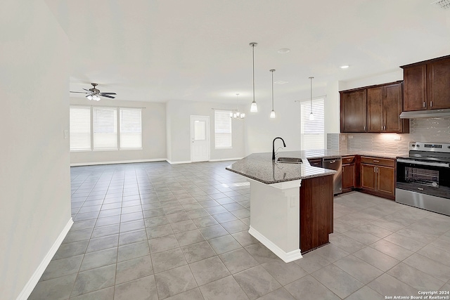 kitchen with appliances with stainless steel finishes, kitchen peninsula, light tile patterned floors, stone countertops, and tasteful backsplash