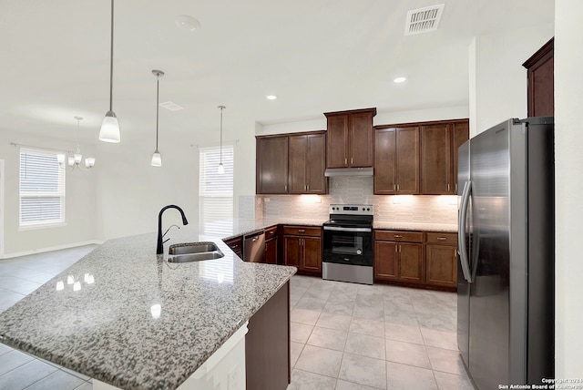 kitchen with appliances with stainless steel finishes, pendant lighting, light tile patterned floors, backsplash, and sink