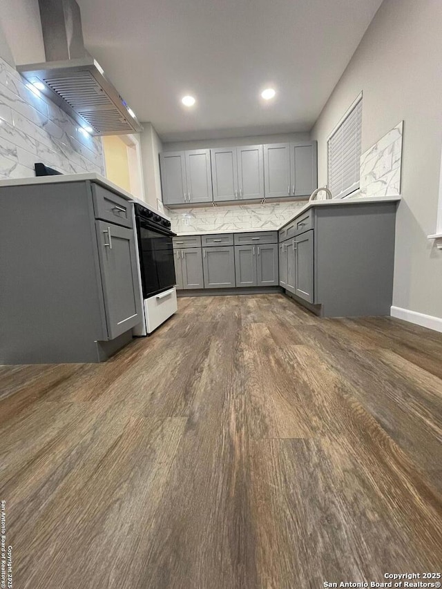 kitchen with dark wood-type flooring, range, gray cabinetry, tasteful backsplash, and island range hood