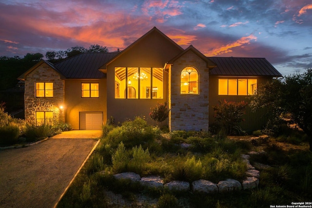 view of front facade featuring stone siding, a standing seam roof, metal roof, and driveway