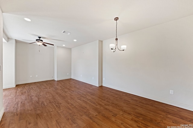 spare room featuring ceiling fan with notable chandelier and hardwood / wood-style floors