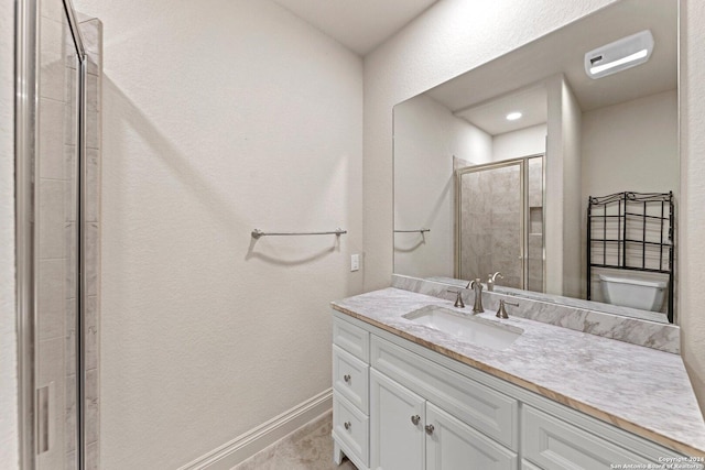 bathroom with toilet, a shower stall, baseboards, and vanity