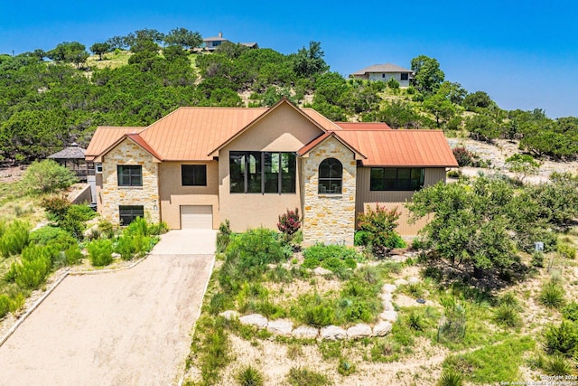 view of front of home featuring metal roof, stone siding, a standing seam roof, and driveway