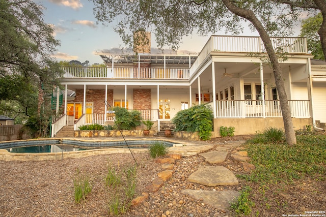 back of property featuring covered porch and a balcony