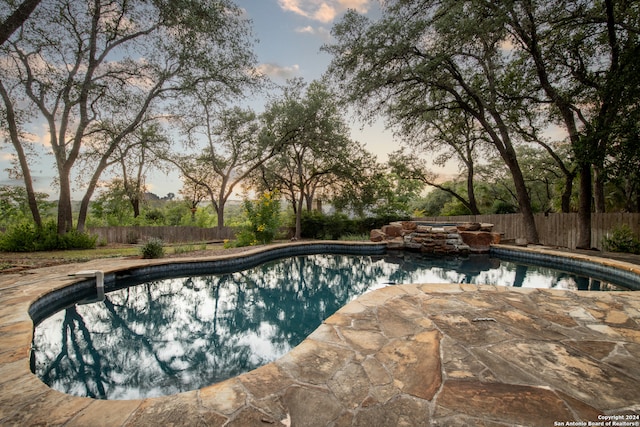 pool at dusk featuring a patio area