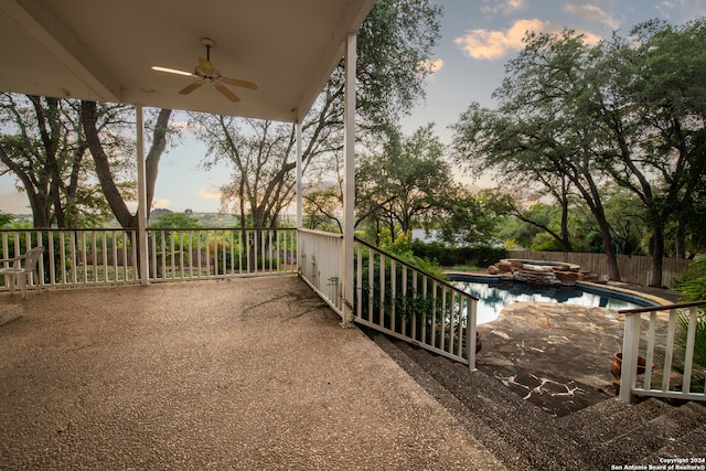 patio terrace at dusk featuring a fenced in pool and ceiling fan