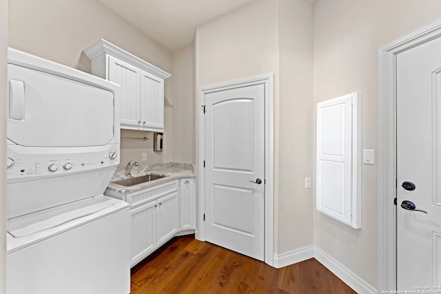 clothes washing area with sink, dark hardwood / wood-style flooring, cabinets, and stacked washing maching and dryer