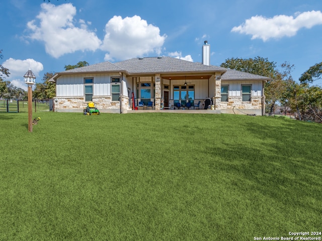 back of property with ceiling fan and a lawn