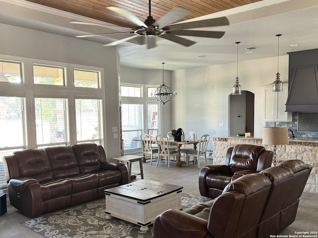 living room featuring ceiling fan with notable chandelier, a wealth of natural light, and wooden ceiling