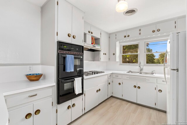 kitchen with black double oven, light hardwood / wood-style floors, white cabinets, sink, and white fridge